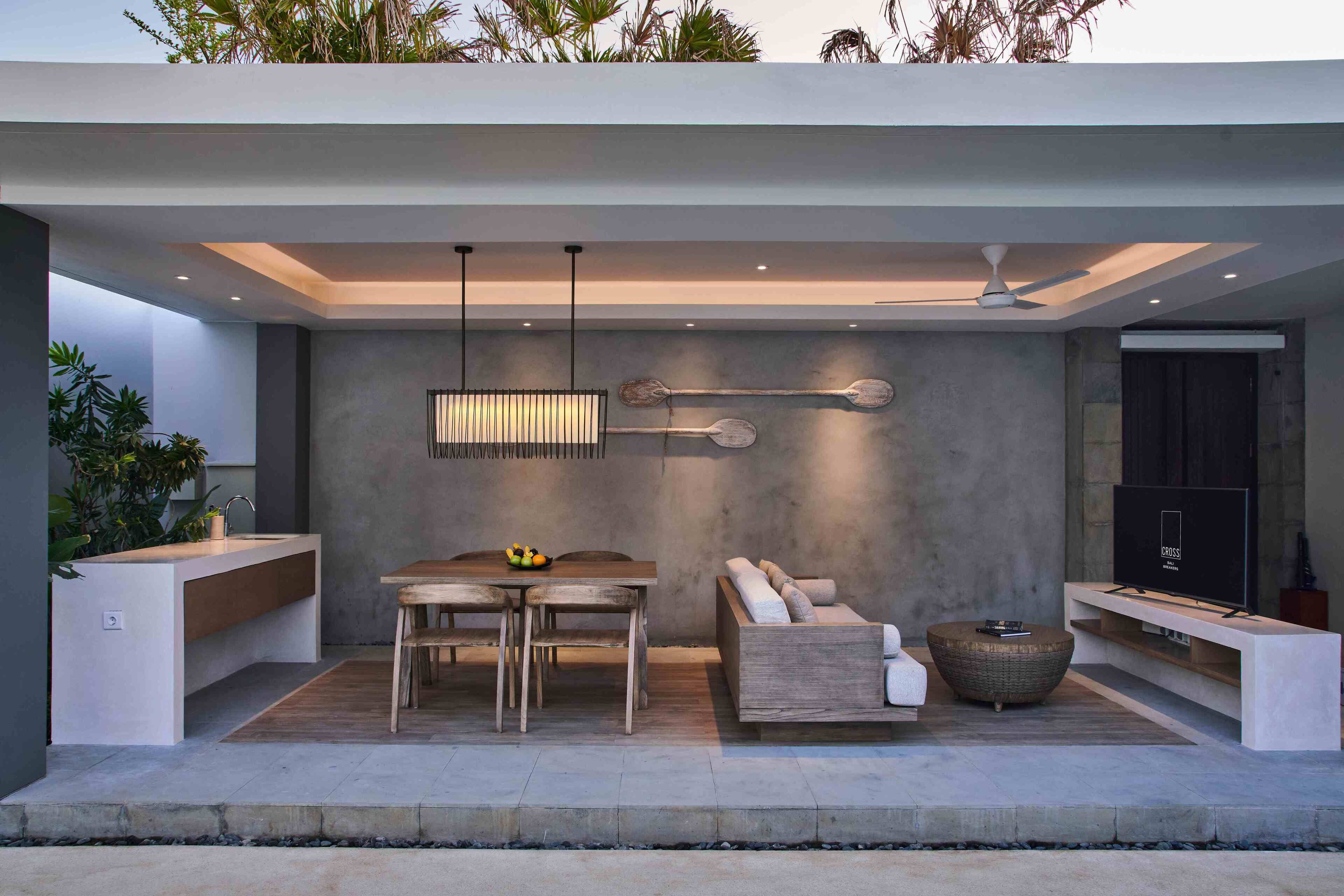 A modern outdoor living space with a dining area, seating, and a TV.