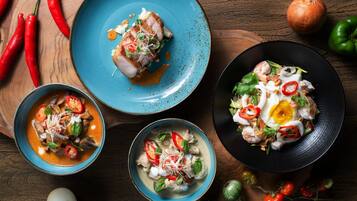 Three bowls of food with various ingredients and vegetables on a wooden table.