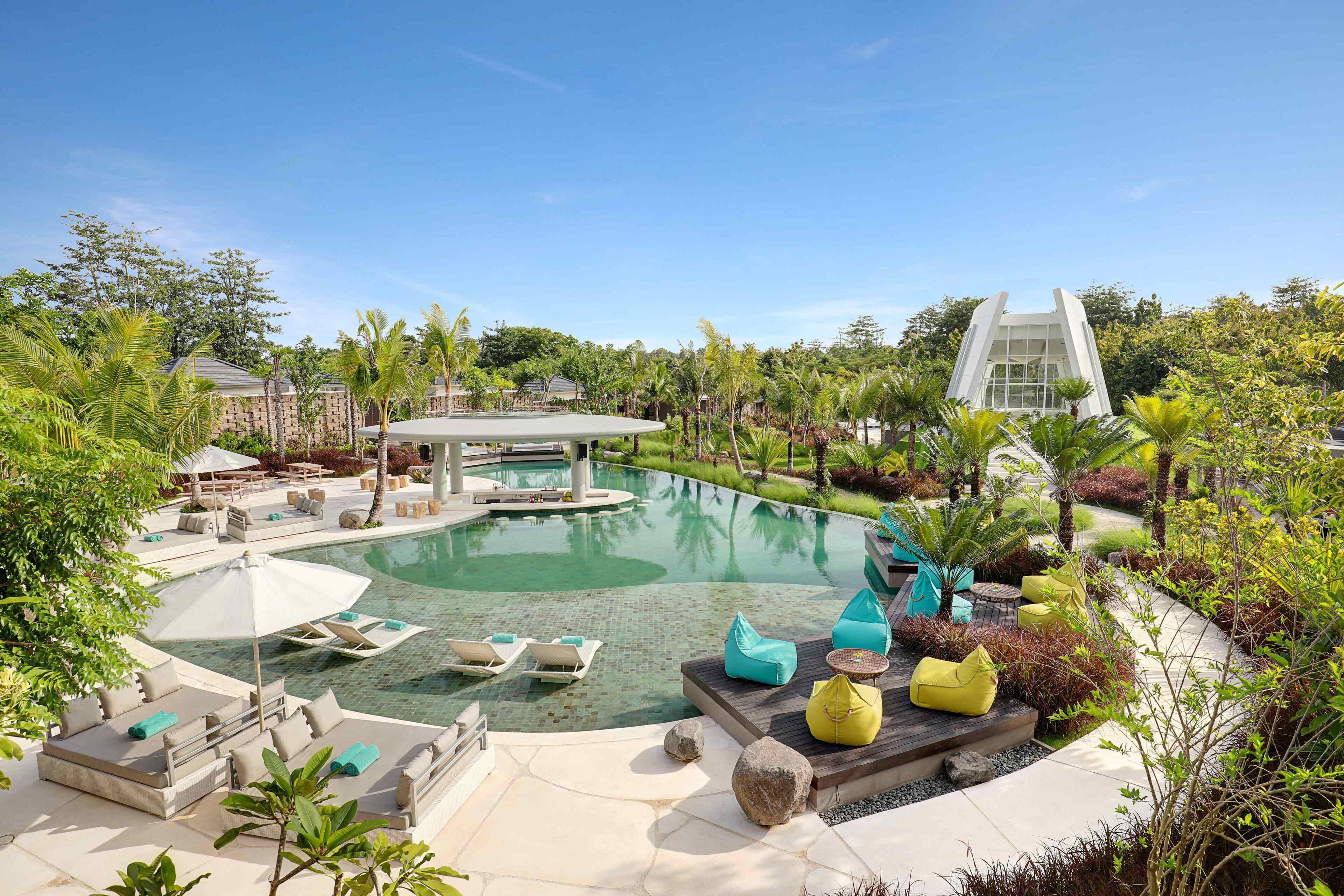 A resort with a large pool, outdoor seating, and lush greenery.