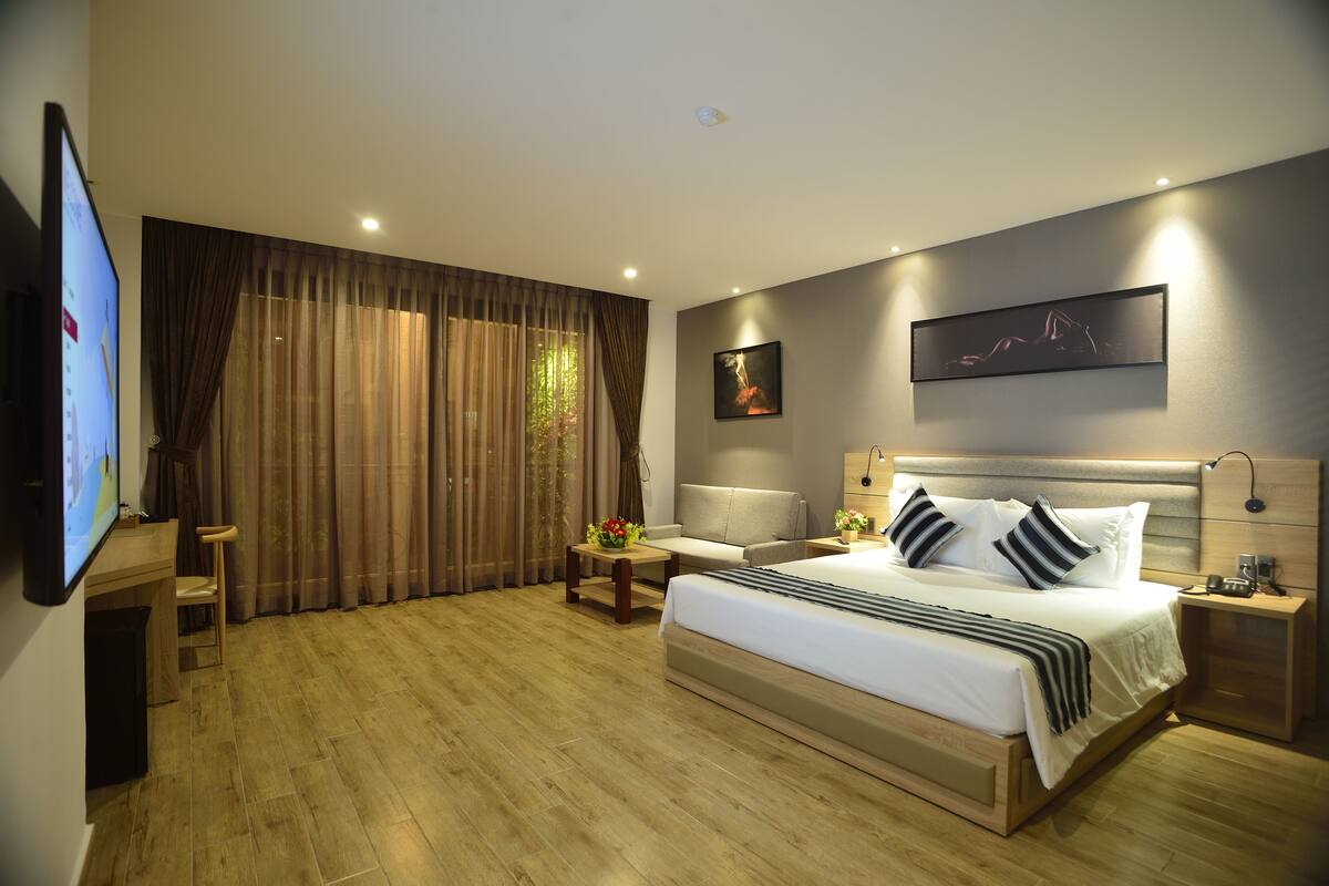 Quarto de hotel moderno com uma cama grande, uma escrivaninha e uma televisão.