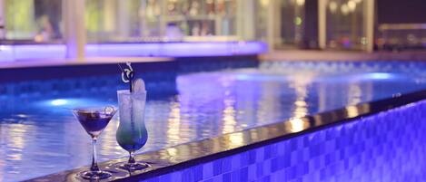 A poolside bar with two drinks and a tiled edge.