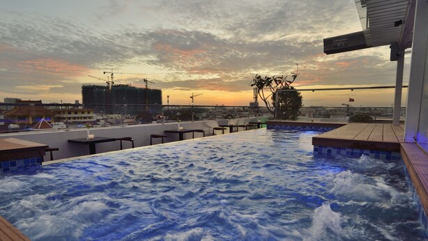 A rooftop infinity pool with a cityscape view during sunset.