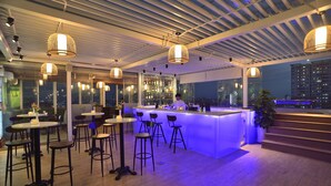 A modern bar area with a bar counter, stools, and pendant lighting.