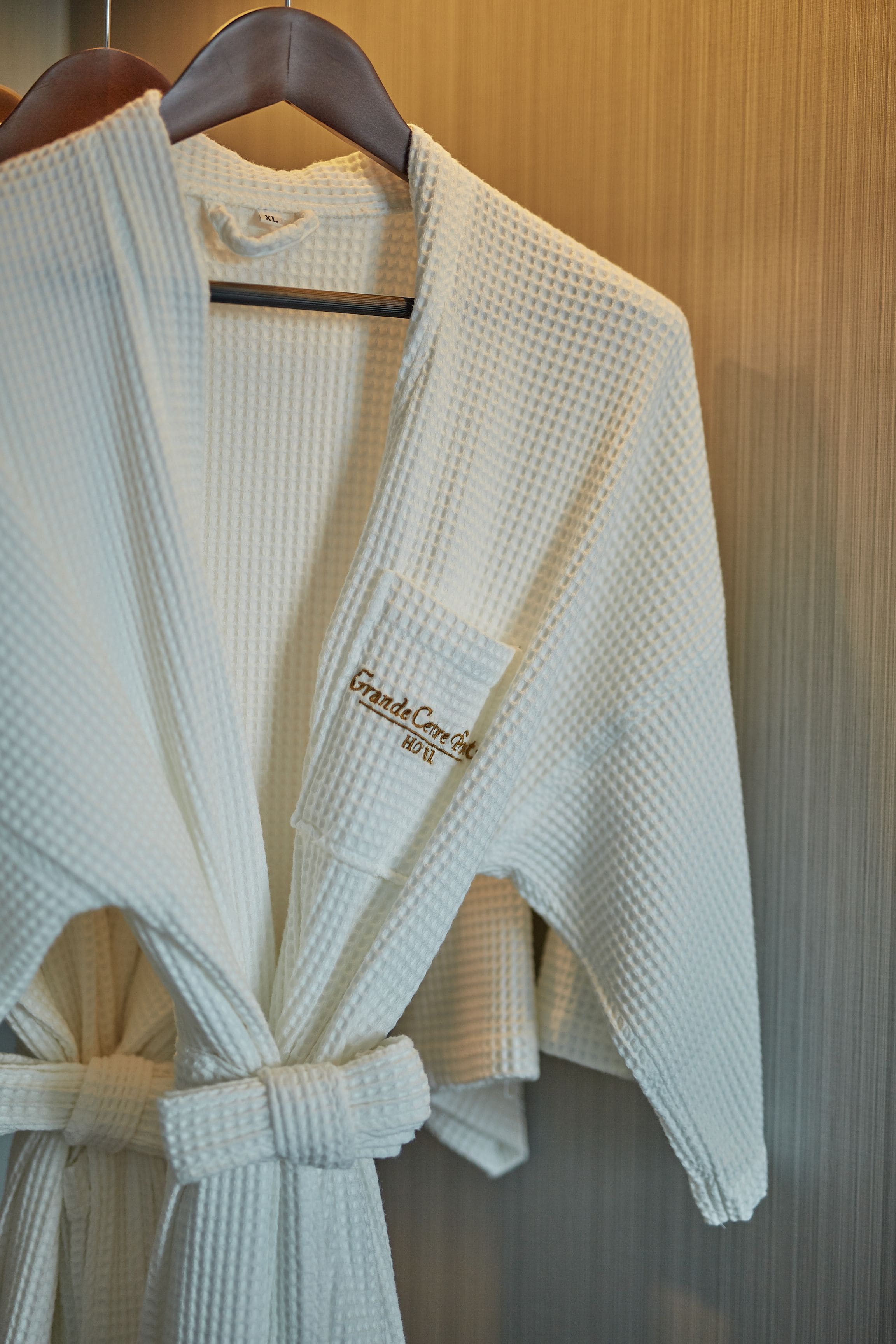 A white robe with a tag reading "Grande Corte Hotel."