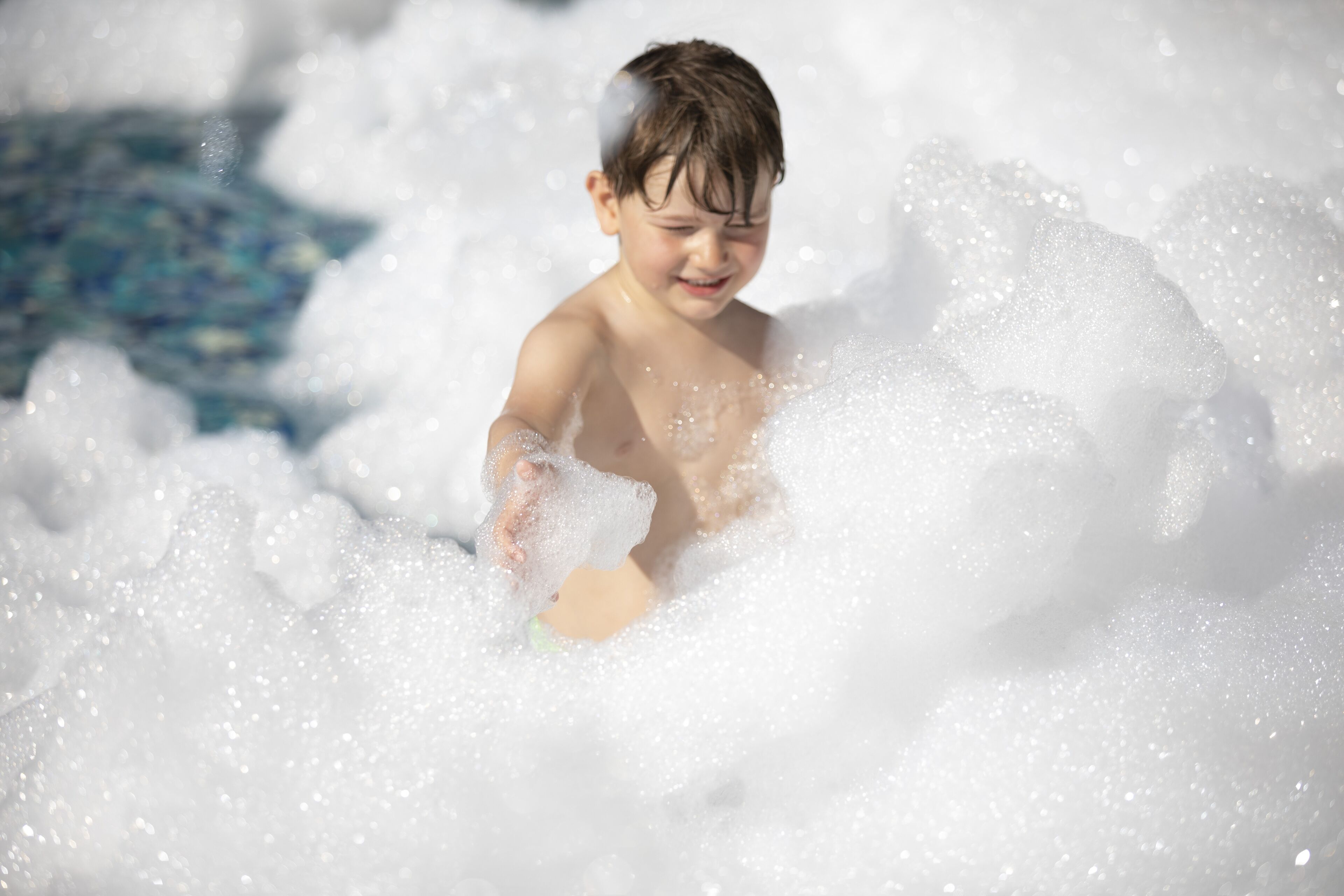 A child playing in a pool with foam.