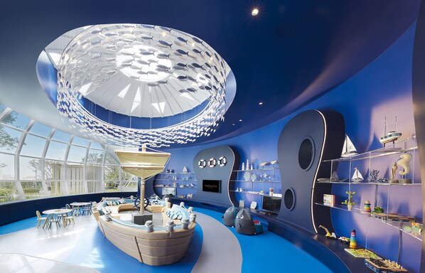 A modern interior with a large spherical ceiling structure, seating areas, and a variety of decorative items on shelves.