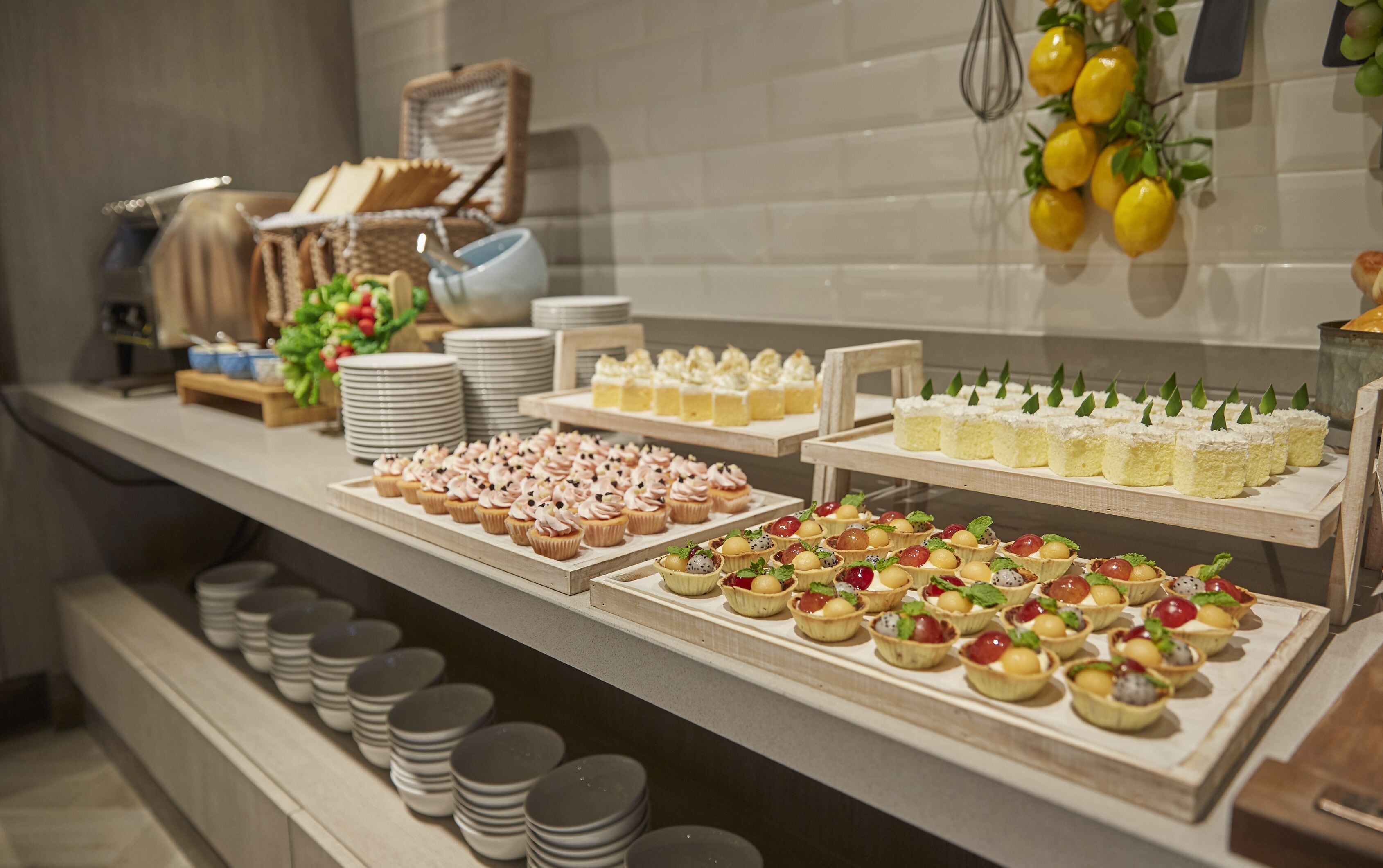 A buffet with various desserts and pastries, including cupcakes and tarts, arranged on a counter with plates and bowls.