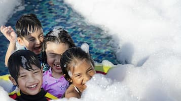 Niños jugando en una piscina con agua y espuma.