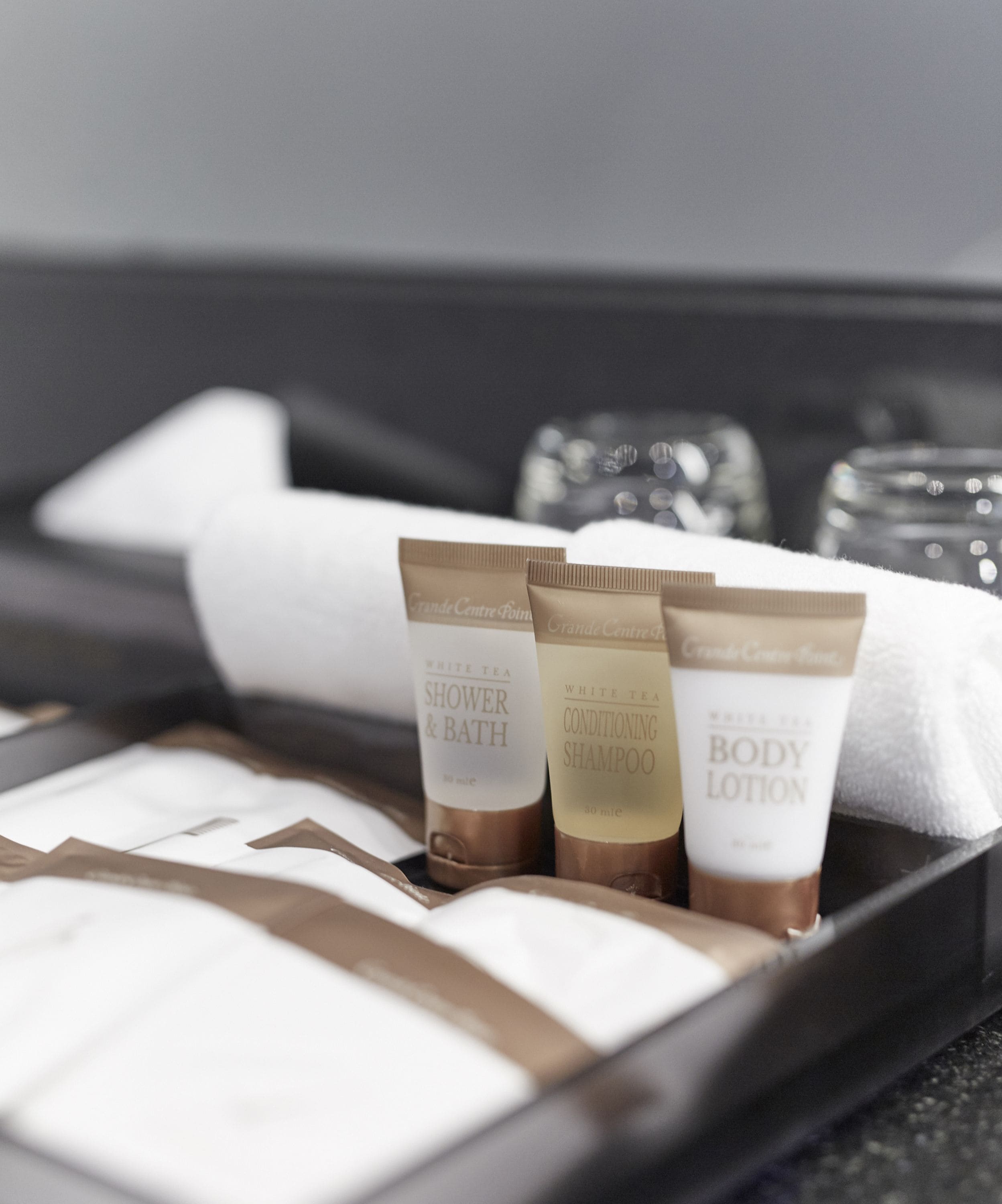 A tray with three toiletry items: shower & bath, conditioning shampoo, and body lotion.