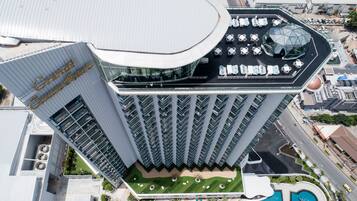 A high-rise hotel with a curved glass facade, multiple balconies, and a rooftop pool area.
