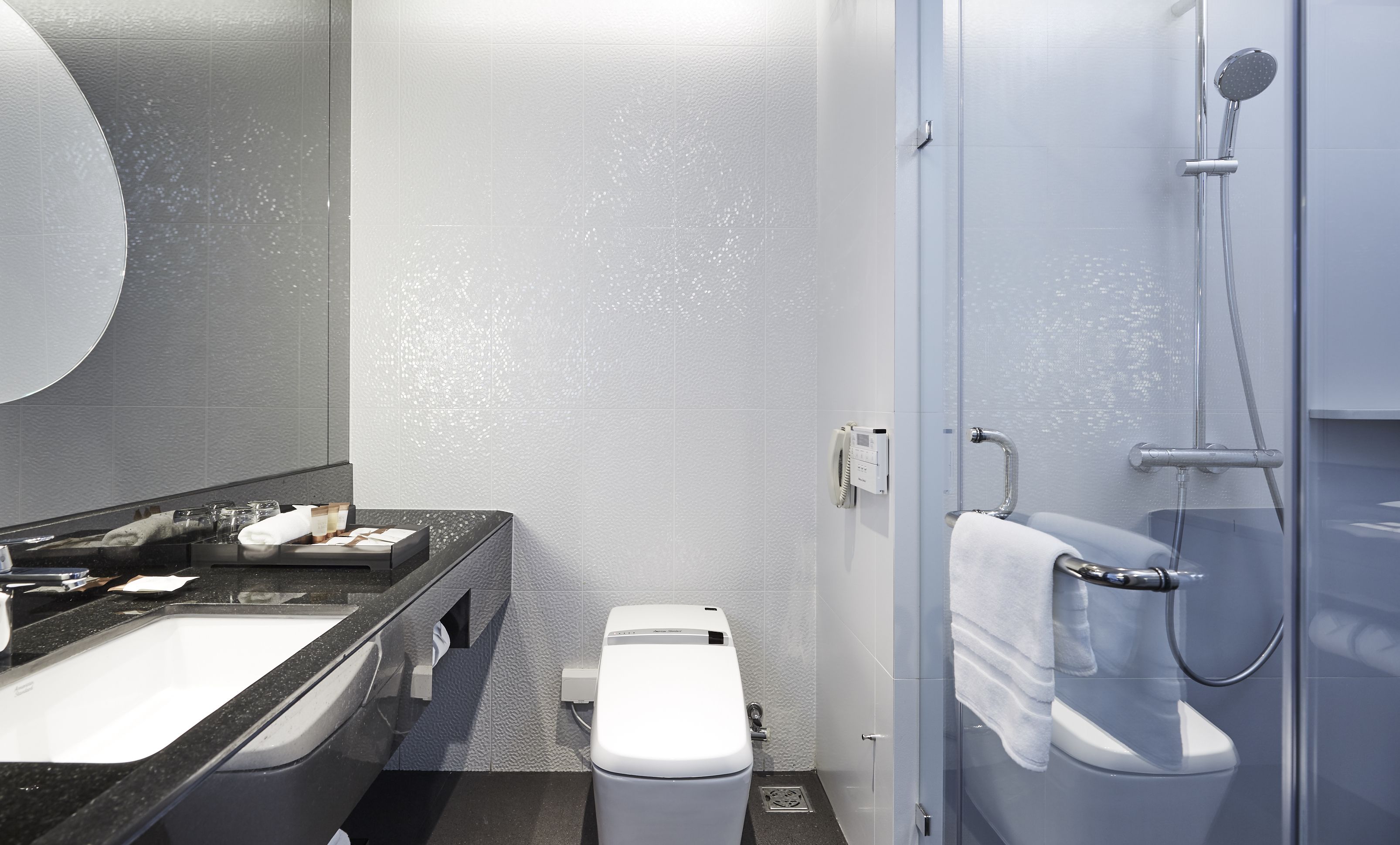 A modern bathroom with a black countertop sink, a white toilet, and a shower area.