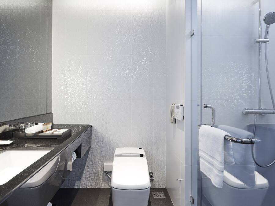 Et moderne badeværelse med en sort bordvask, et hvidt toilet og et bruseområde.