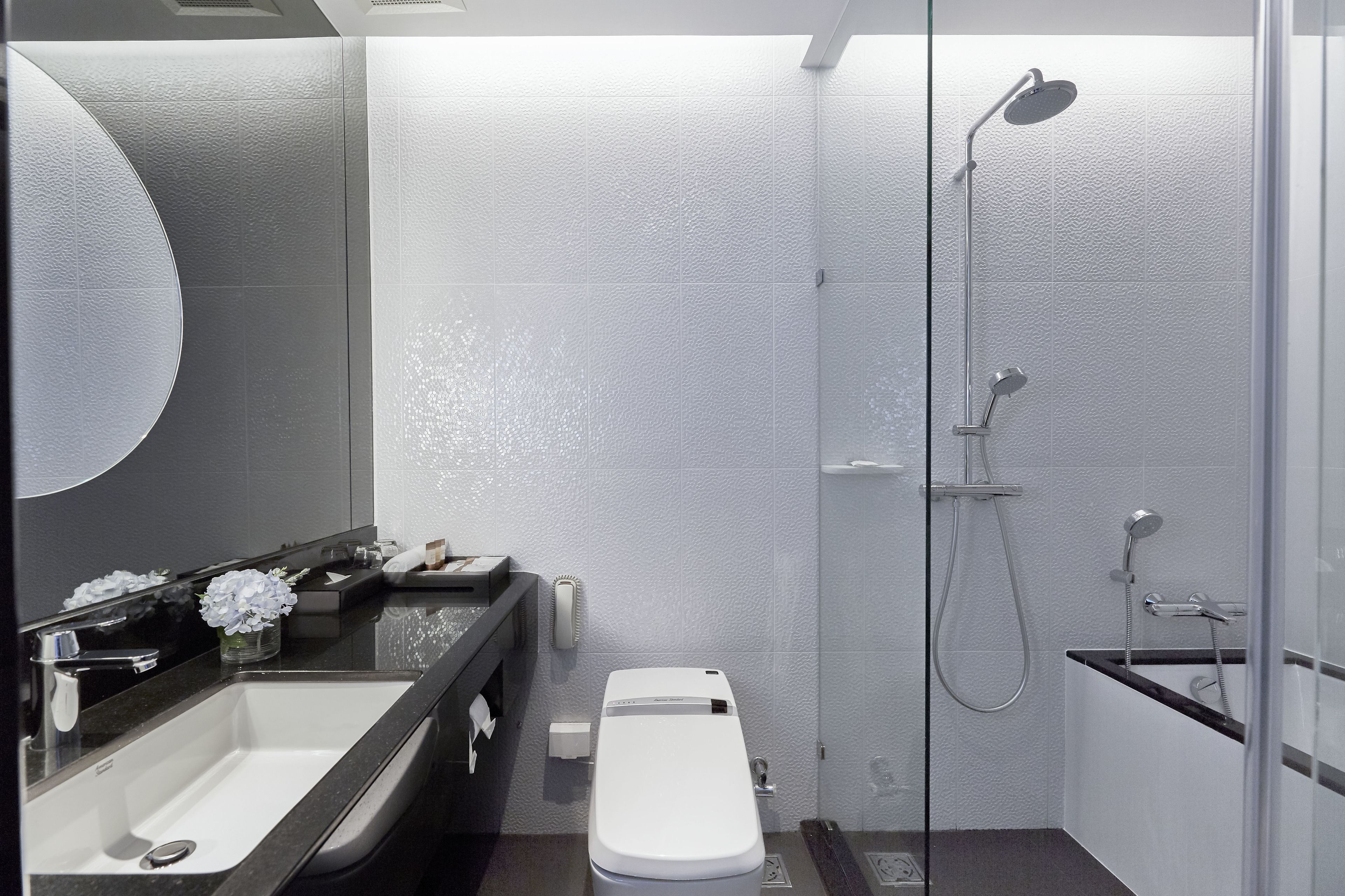 Ein modernes Badezimmer mit großem Spiegel, Waschbecken, Toilette und Duschbereich.