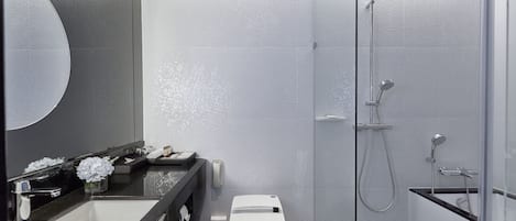 A modern bathroom with a large mirror, a sink, a toilet, and a shower area.