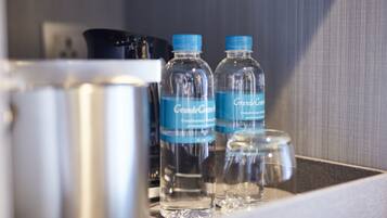 A minibar with two GrandeCafé water bottles and a glass jar.