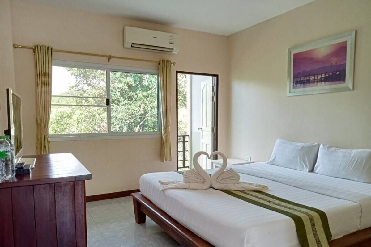 Quarto de hotel com cama, escrivaninha e janela com cortinas.
