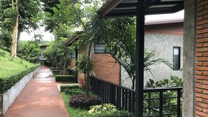 Un sendero bordeado de vegetación y un edificio de ladrillo con un porche cubierto.