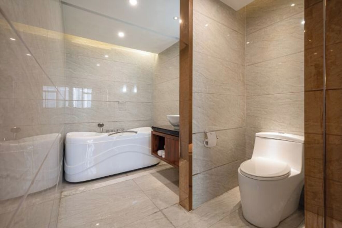 A modern bathroom with a large bathtub, a toilet, and a wooden vanity.