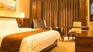 Ein Hotelzimmer mit einem großen Bett, einem Schreibtisch, einem Sessel und einem Fernseher.