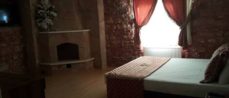Een slaapkamer met een open haard, een bed en een televisie.