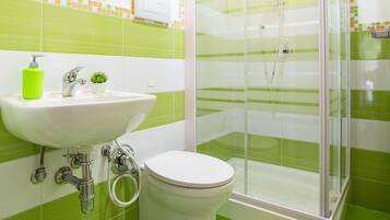 A bathroom with a shower, sink, toilet, and a small potted plant.