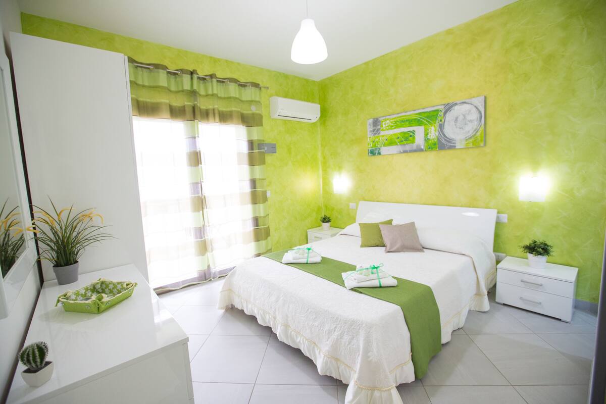 Una habitación luminosa con una cama, mesitas de noche y una ventana con cortinas.