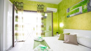 A hotel room with a bed, a green wall, a window with curtains, and an air conditioning unit. - B&B Pepito (Cefalù)