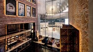Een ruime lobby met een hoge plafond, een bar met glazenplanken, en een zithoek met uitzicht door grote ramen.