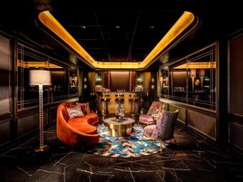 Un salon luxueux doté d’un bar, de fauteuils confortables et d’un tapis à motifs.
