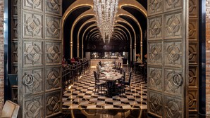 Een weelderig interieur met een zwart-wit schachoot patroon, een centrale kroonluchter en gedetailleerd houtwerk.