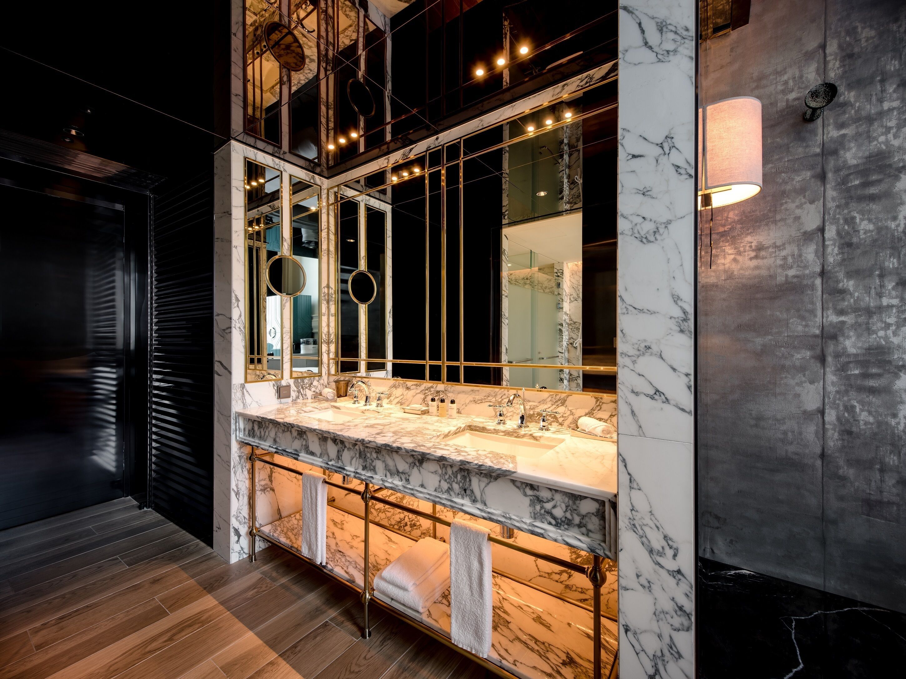 A modern bathroom with a large mirror, marble countertops, and a towel rack.