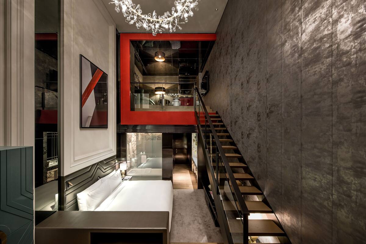A modern interior with a staircase, a bed, and a chandelier.