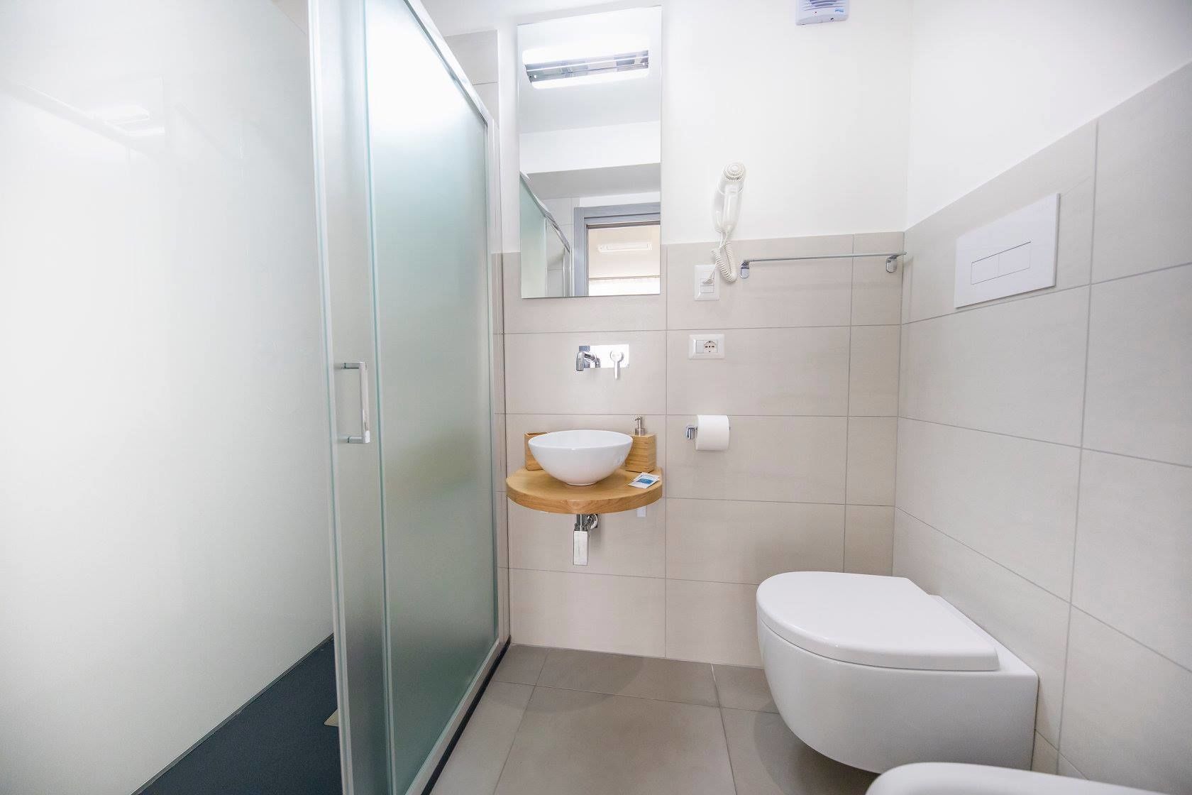 A modern bathroom with a glass shower enclosure, a white toilet, and a wooden vanity with a sink.