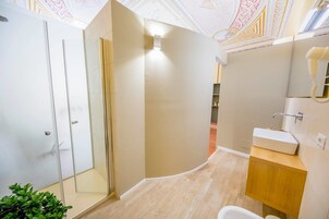 Un baño moderno con ducha de vidrio, lavamanos blanco y tocador de madera.