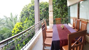A balcony with a table and chairs, surrounded by greenery and a glass railing. - Hotel Scarlet Bukit Pakar (Bandung)
