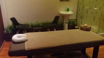 Relax in a serene space with a massage table, a small table for refreshments, and a potted plant.