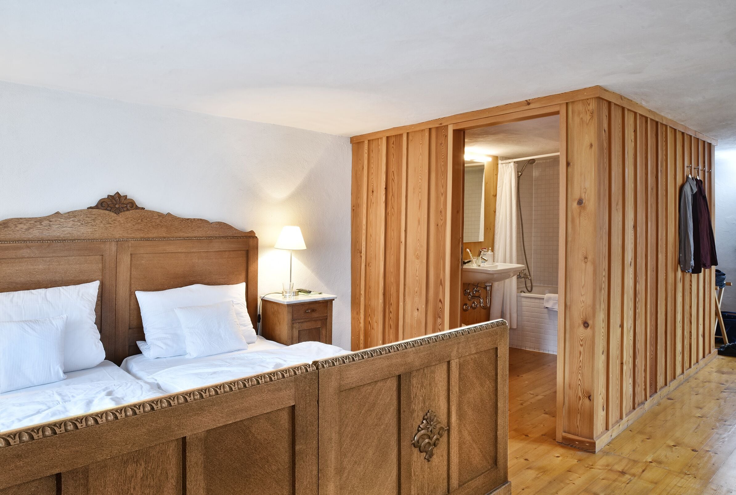 Un dormitorio con estructura de madera, una cama, una mesita de noche y un armario de madera.