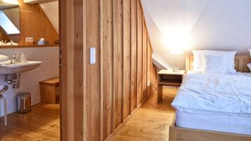 Un dormitorio con cabecera de madera, una mesita de noche, una lámpara y una colcha blanca.