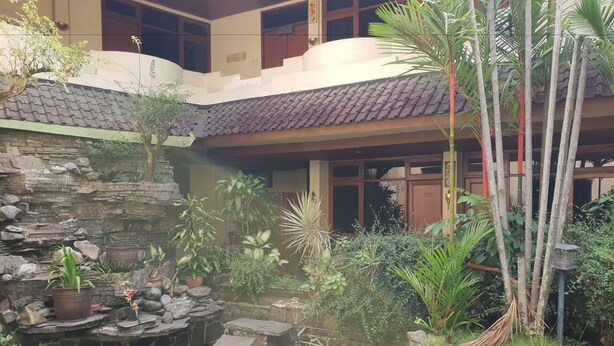 A courtyard with a small pond, stone steps, and various potted plants. - Hotel Dequr Bandung (Bandung)