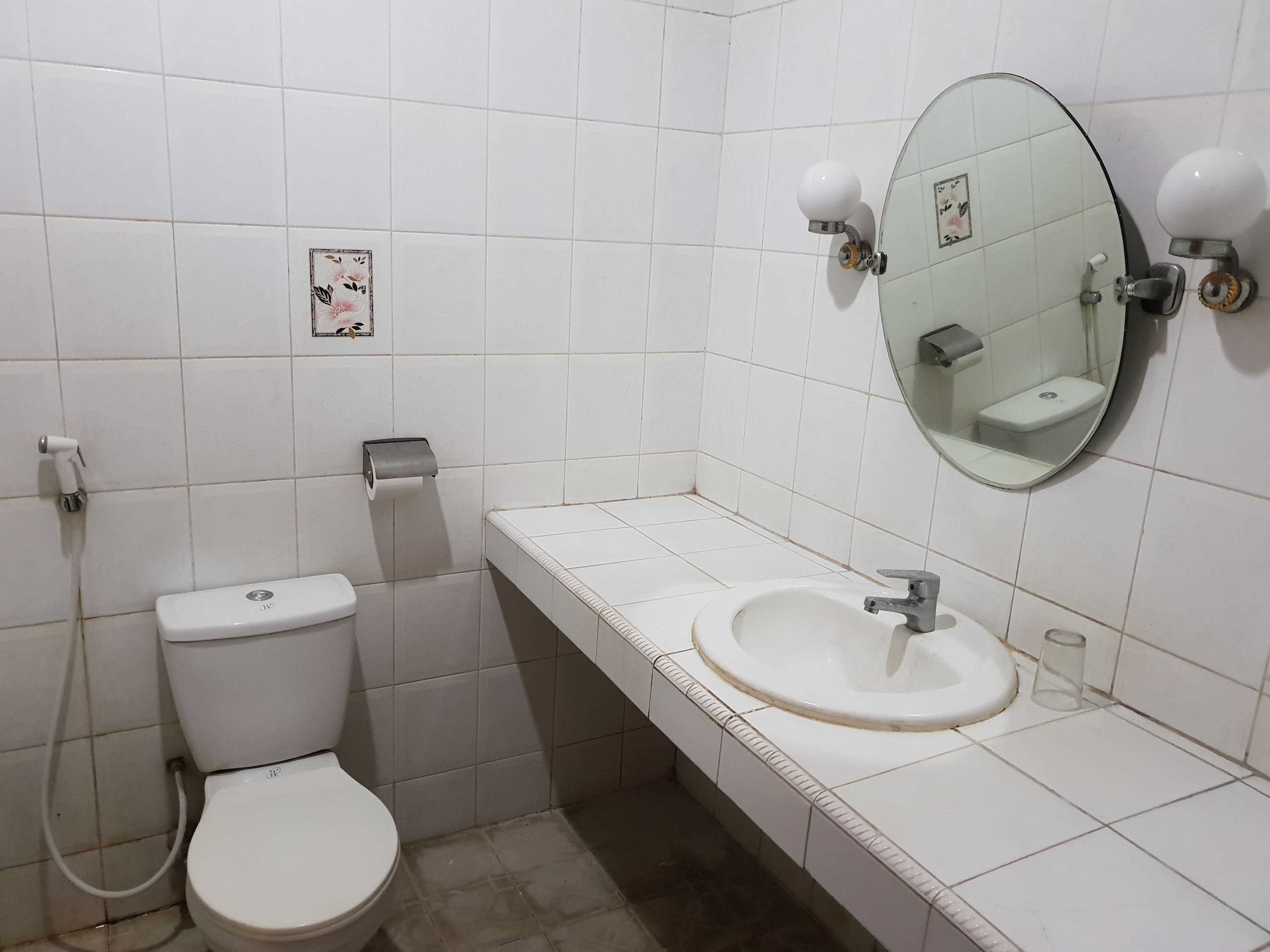 Ein Badezimmer mit Toilette, Waschbecken, Spiegel und Toilettenpapierhalter.