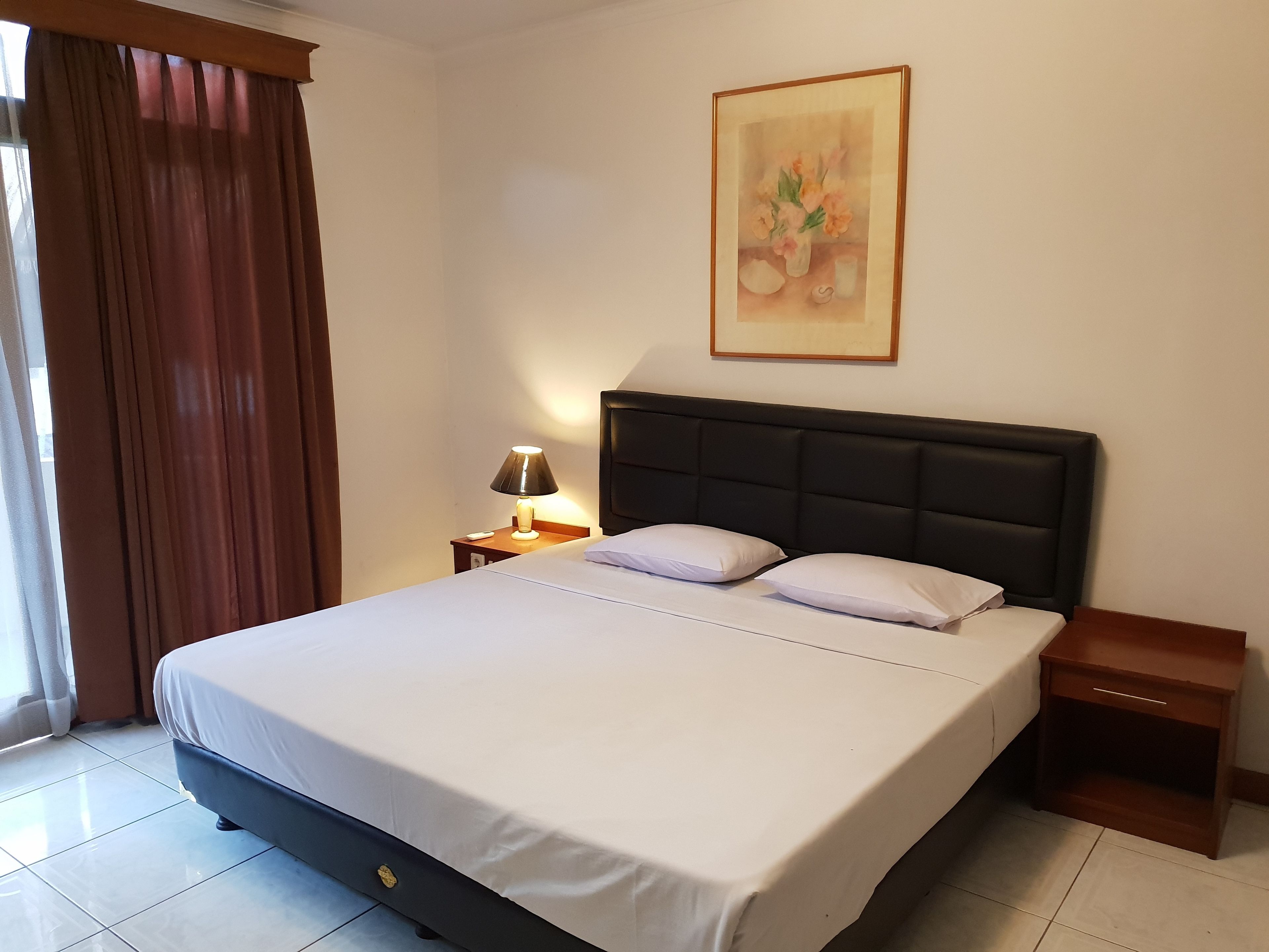 A neatly made bed with a headboard, a bedside lamp, and a nightstand.