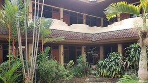 A courtyard with a central water feature, surrounded by various tropical plants and a stone wall. - Hotel Dequr Bandung (Bandung)