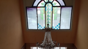 A staircase with a chandelier, a stained glass window, and a view outside. - Hotel Dequr Bandung (Bandung)