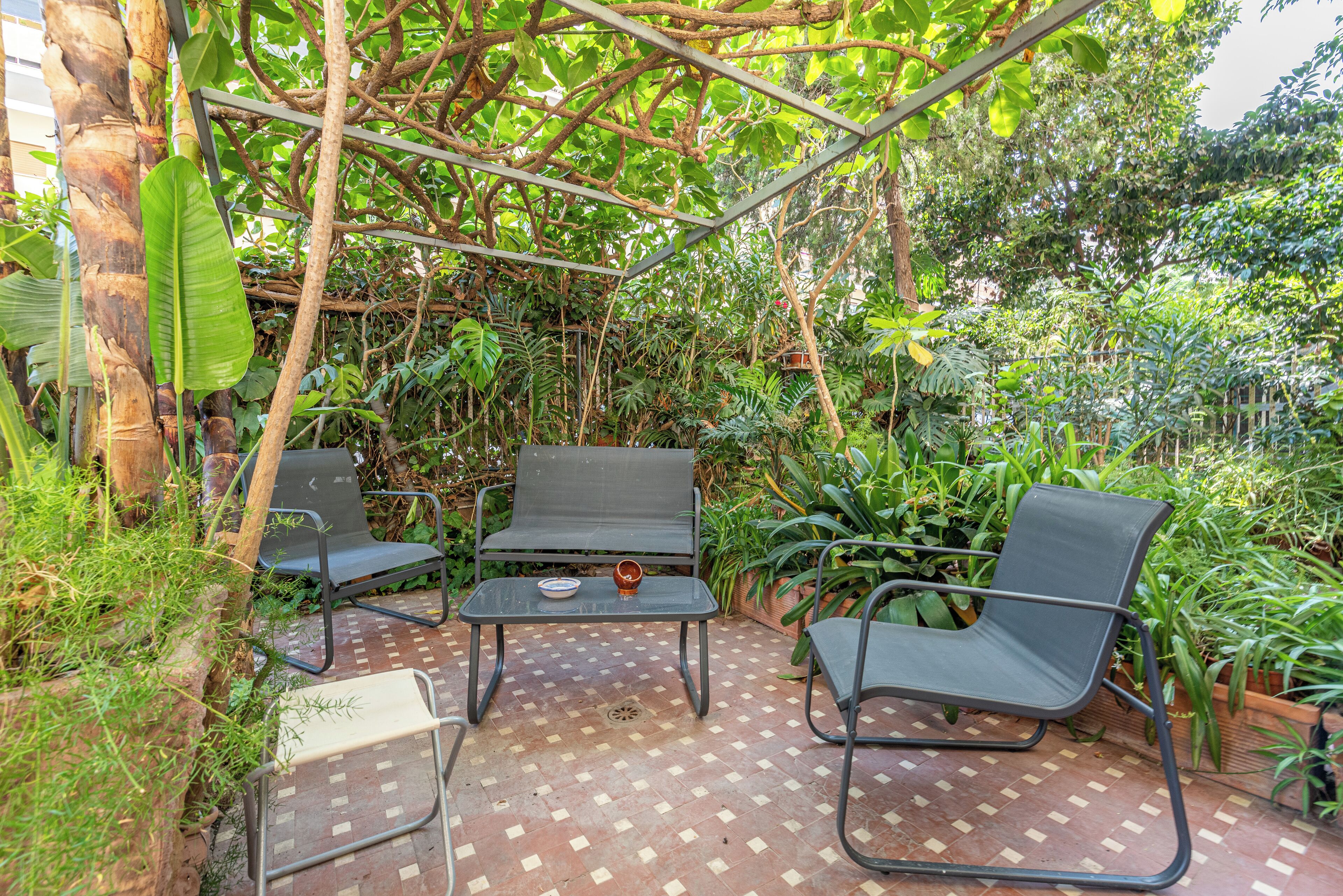 An outdoor patio with two metal chairs, a small table, and a bench.