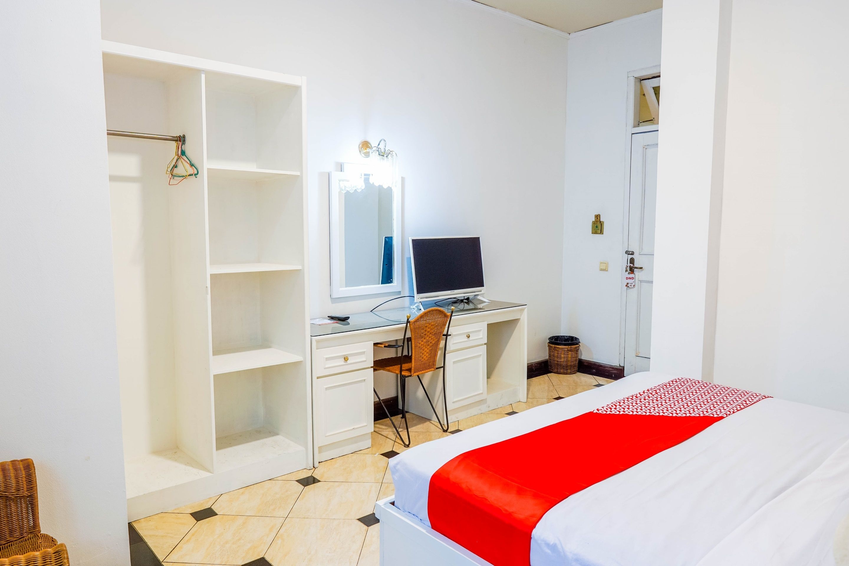 Ein Hotelzimmer mit einem Bett, einem Schreibtisch mit Computer, einem Stuhl und einem Kleiderschrank.