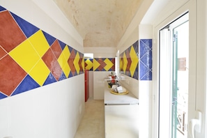 Stylish hallway leads to a modern kitchen with a white countertop and sink.