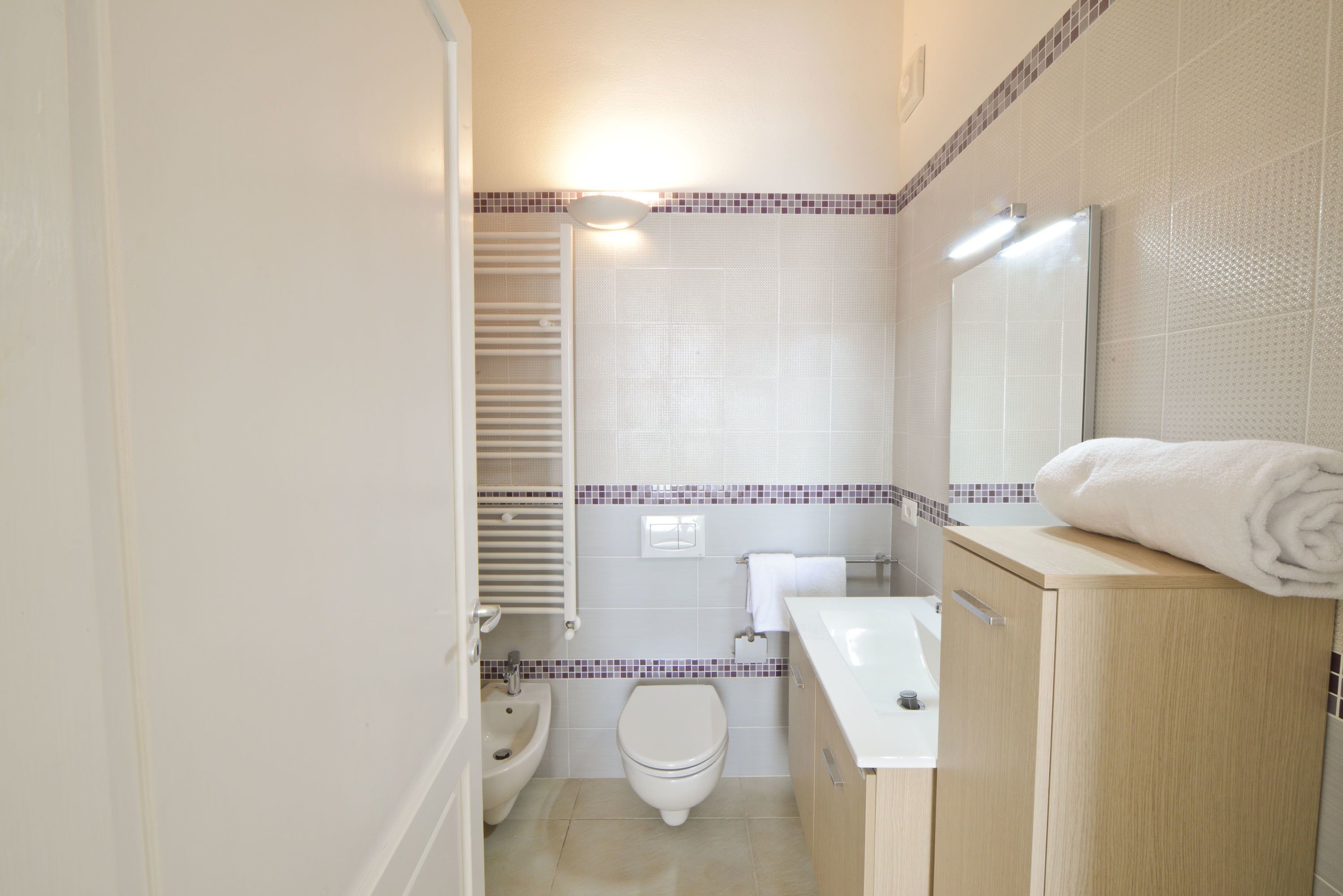 Ein modernes Badezimmer mit Toilette, Bidet, Waschbecken und einem Spiegel darüber.