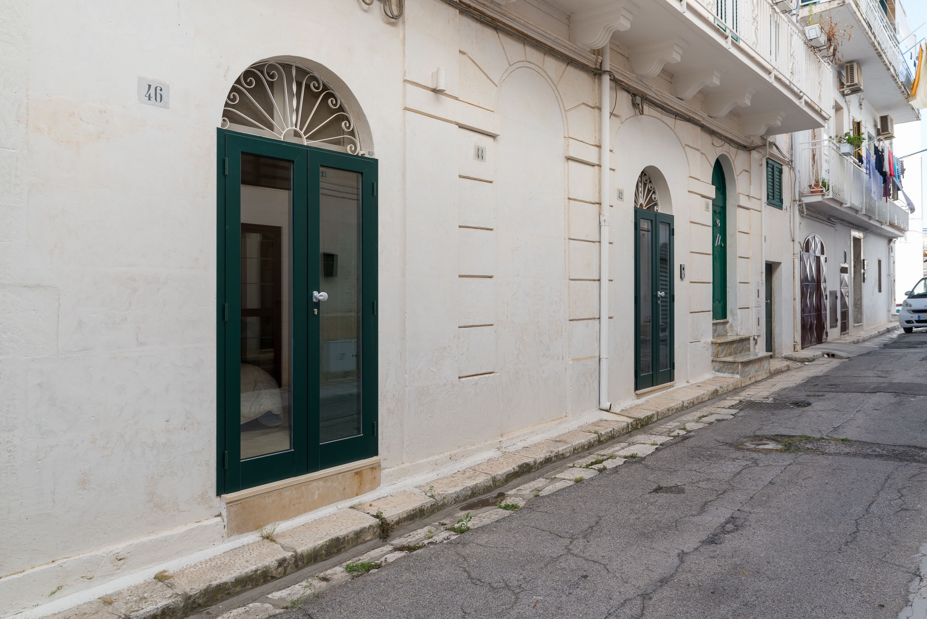 Una hilera de edificios con puertas verdes y paredes blancas, numerados 46.