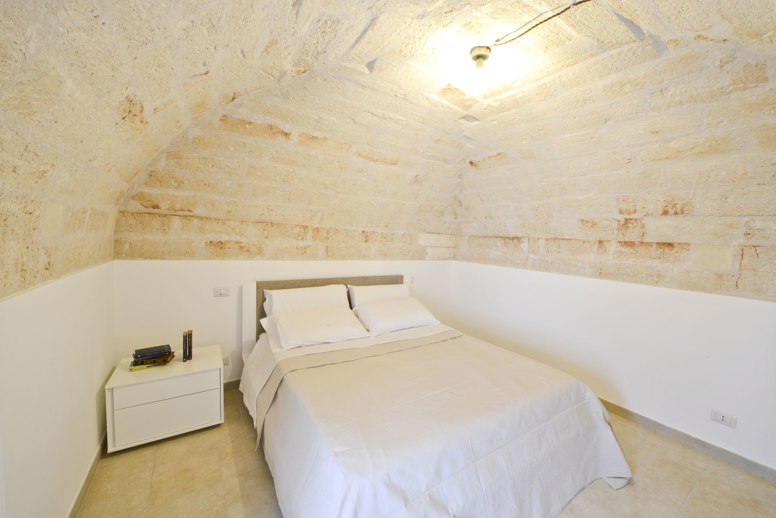 A bedroom with a single bed, a nightstand, and a ceiling light.