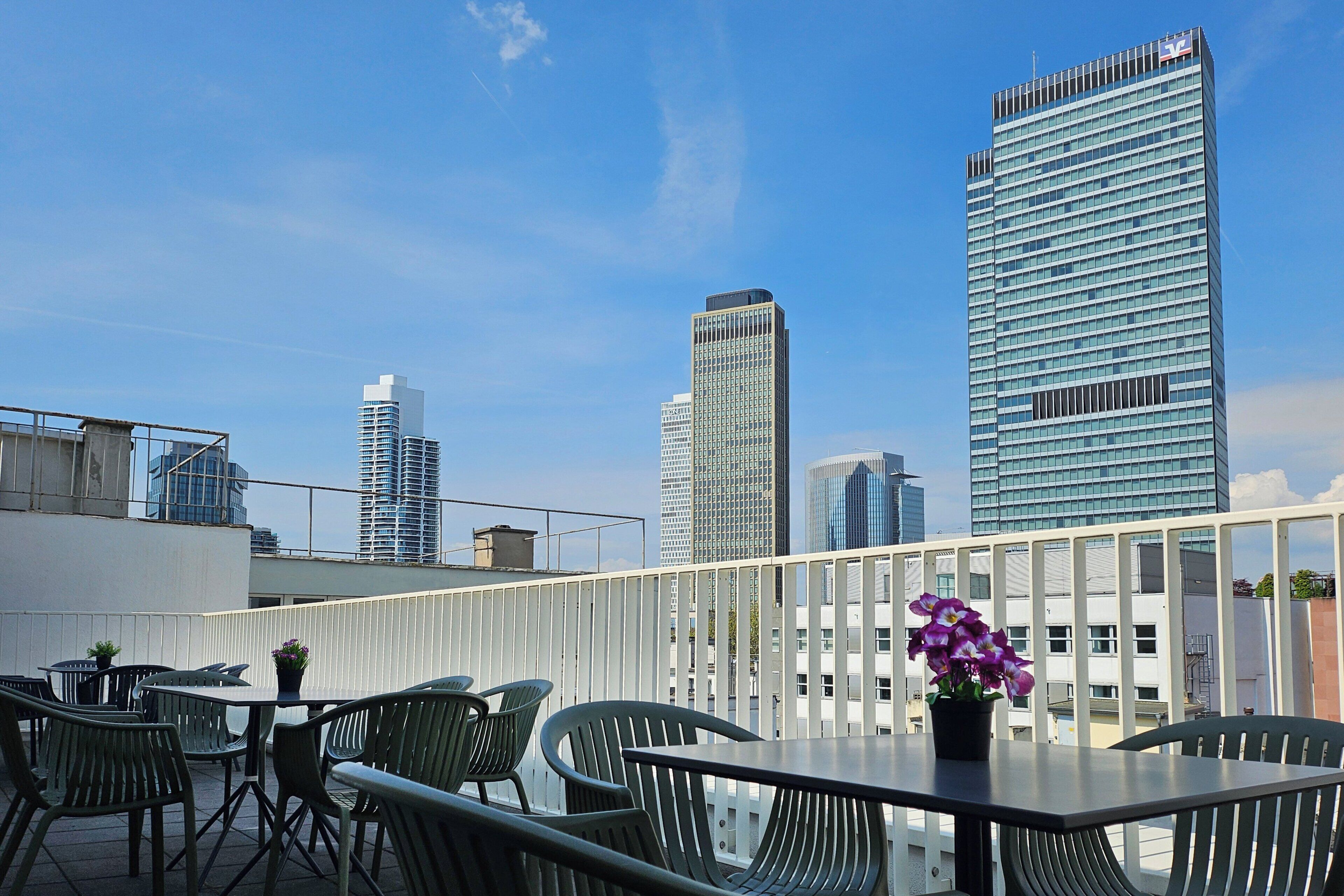 A rooftop terrace with outdoor seating and a view of tall buildings.